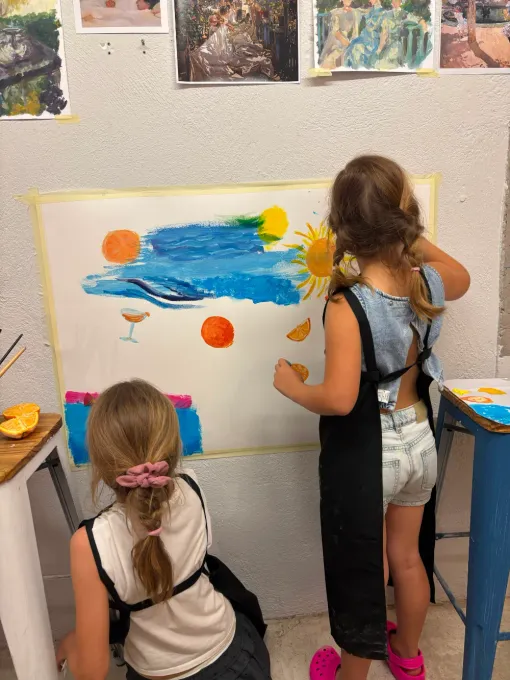 Dos niños pintando un mural colorido en una pared blanca en un estudio de arte.