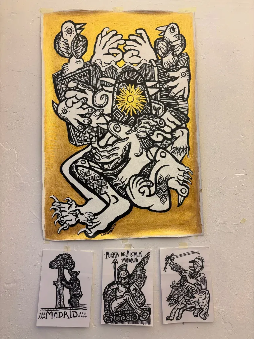 Figura abstracta en blanco y negro sobre papel amarillo, encima de tres pequeños bocetos impresos sobre una pared blanca.