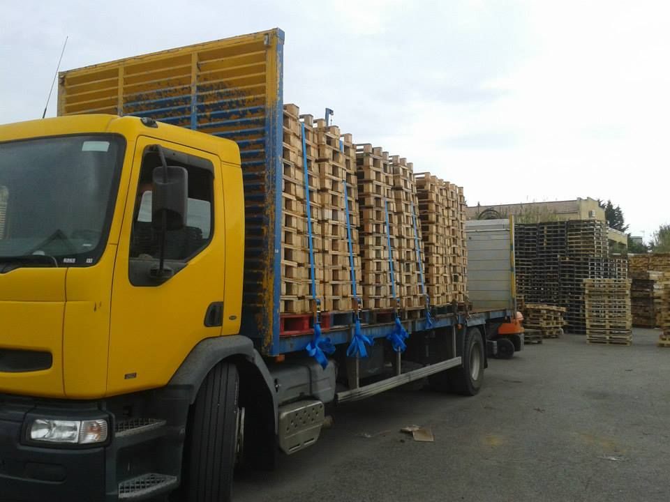 Camion jaune et bleu transportant des palettes.