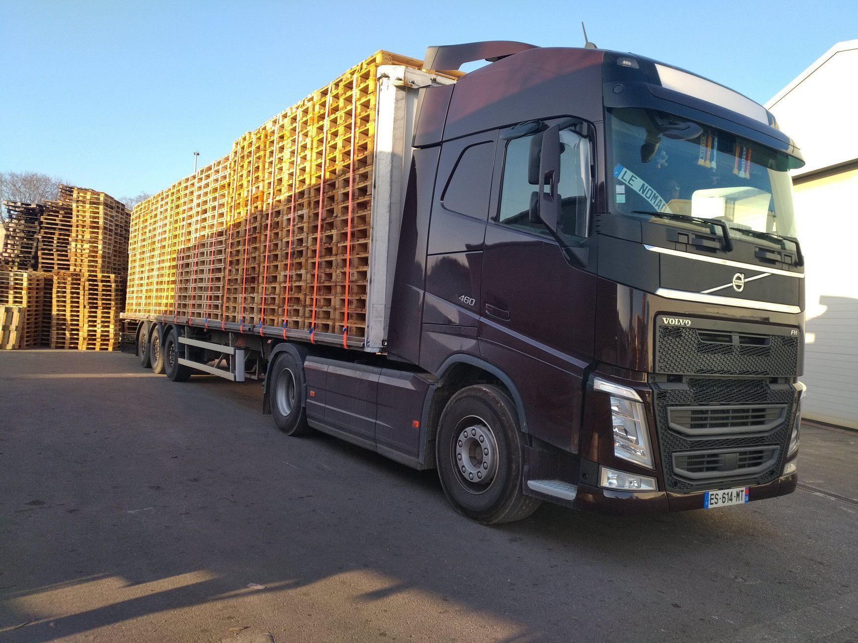Camion noir transportant des palettes.