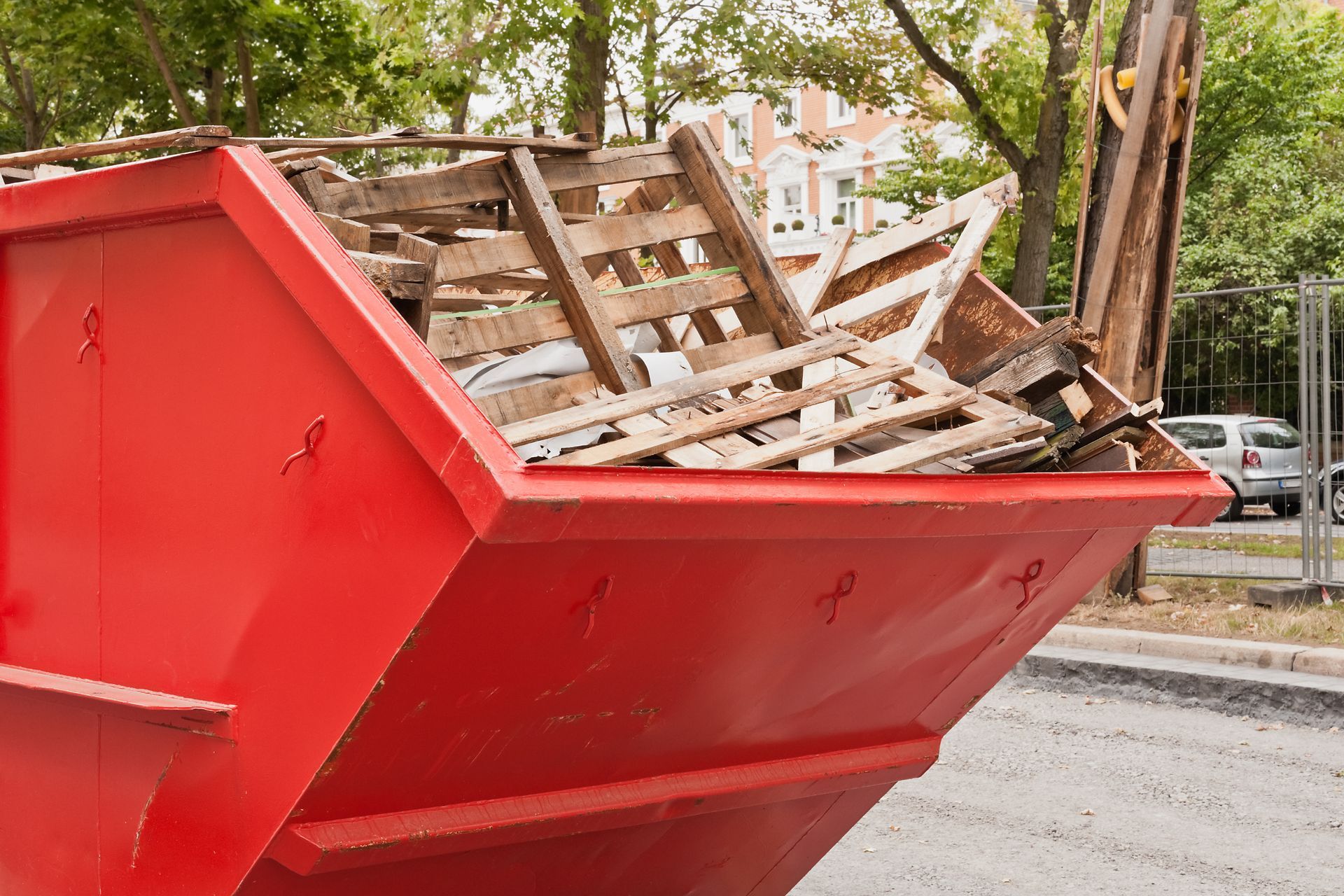 Benne rouge remplie de déchets de palettes en bois.