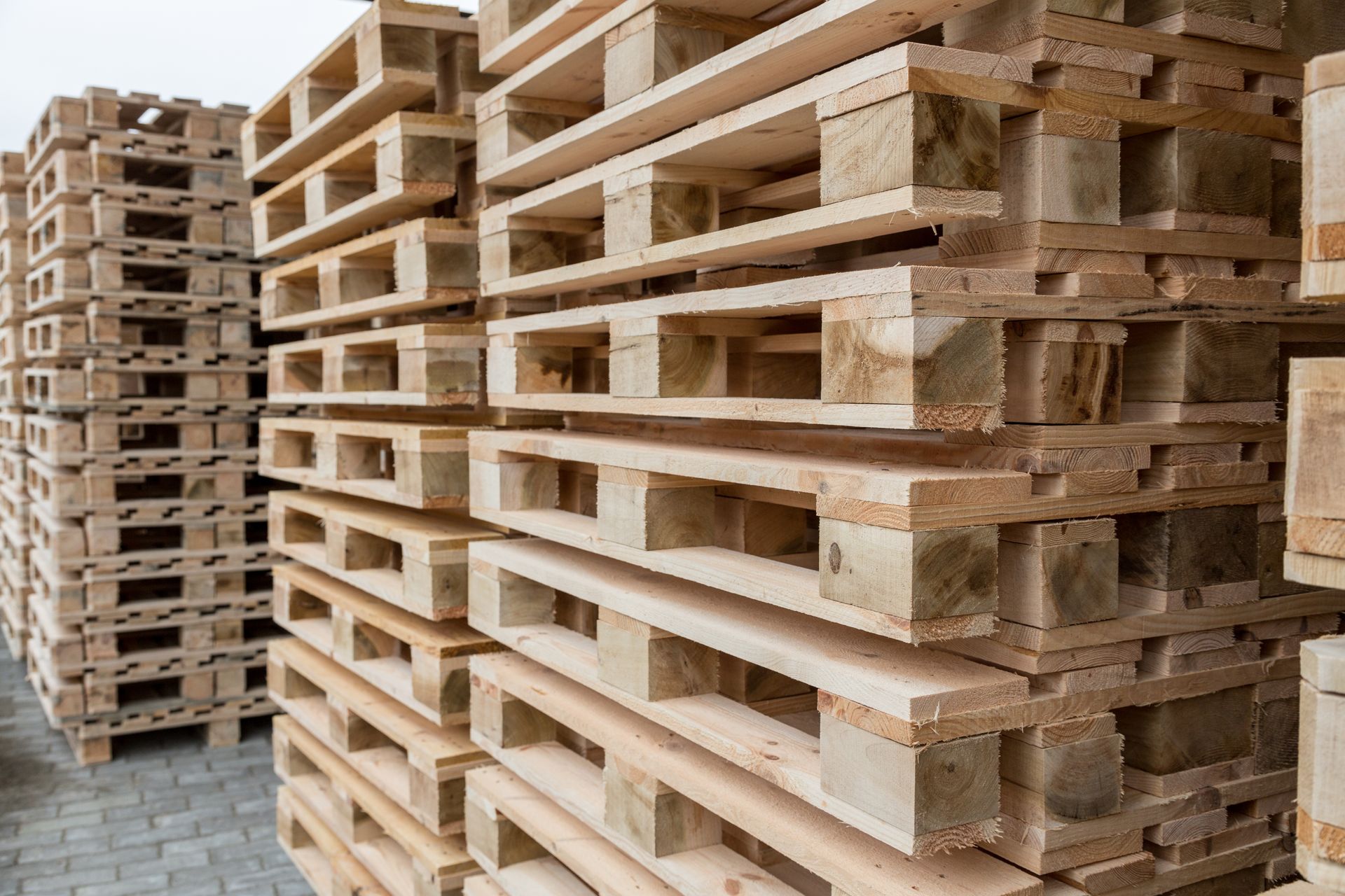 Piles de palettes en bois sur un sol gris.