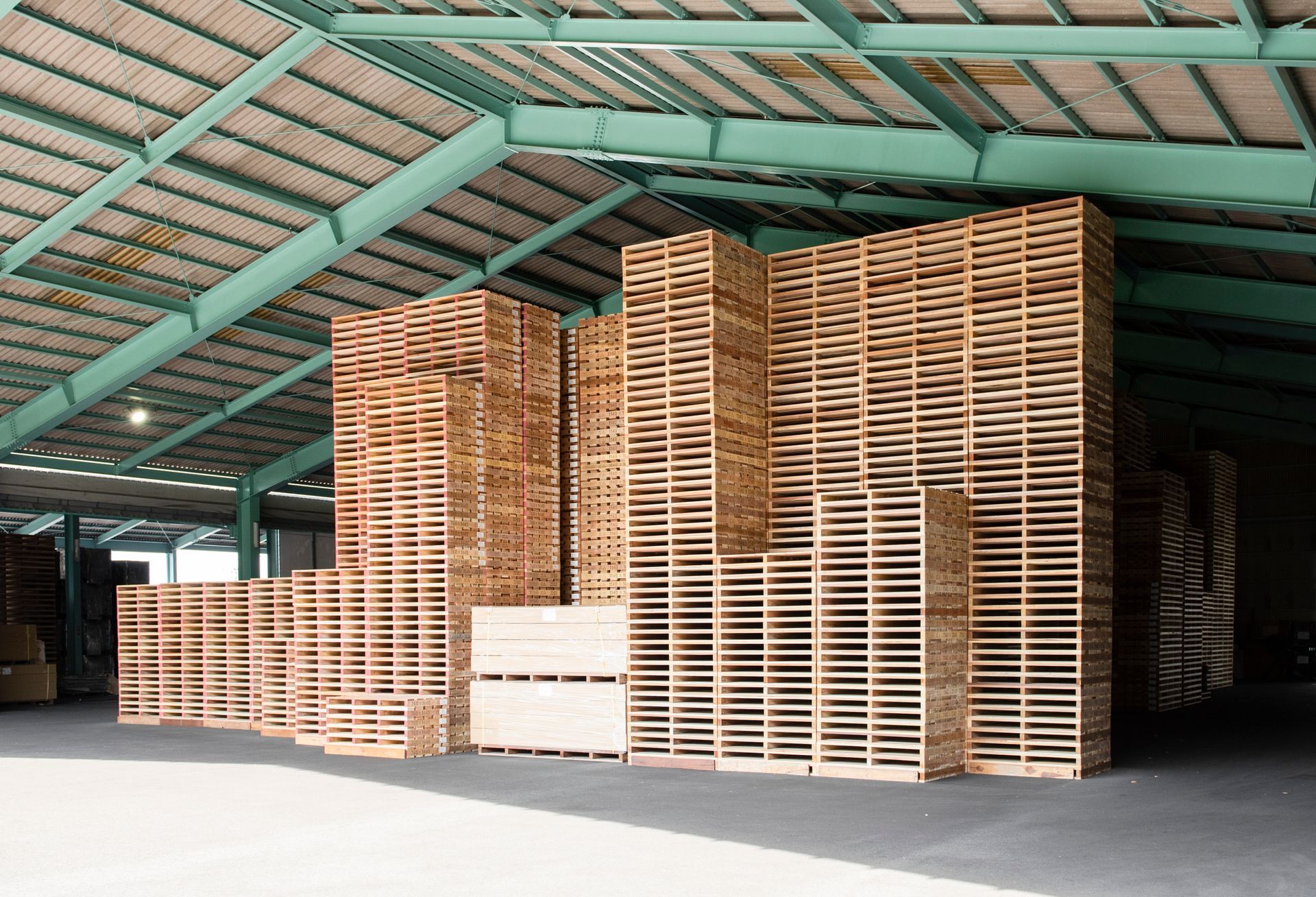 Entrepôt avec plusieurs piles de palettes en bois.