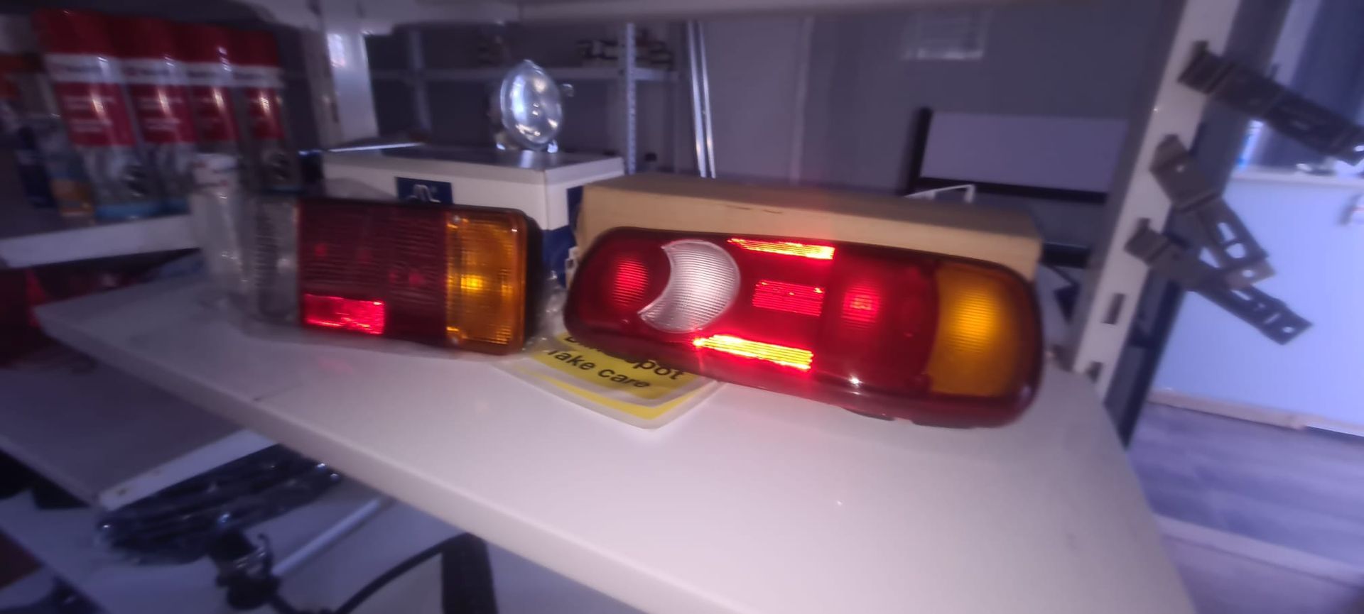 Hay dos luces traseras en un estante en una habitación oscura.
