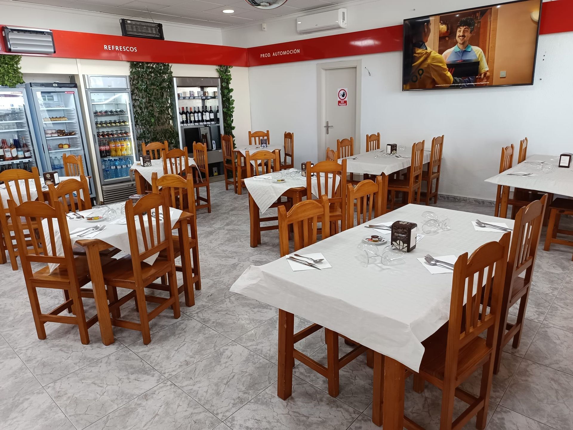 Un restaurante con mesas y sillas y un televisor en la pared.