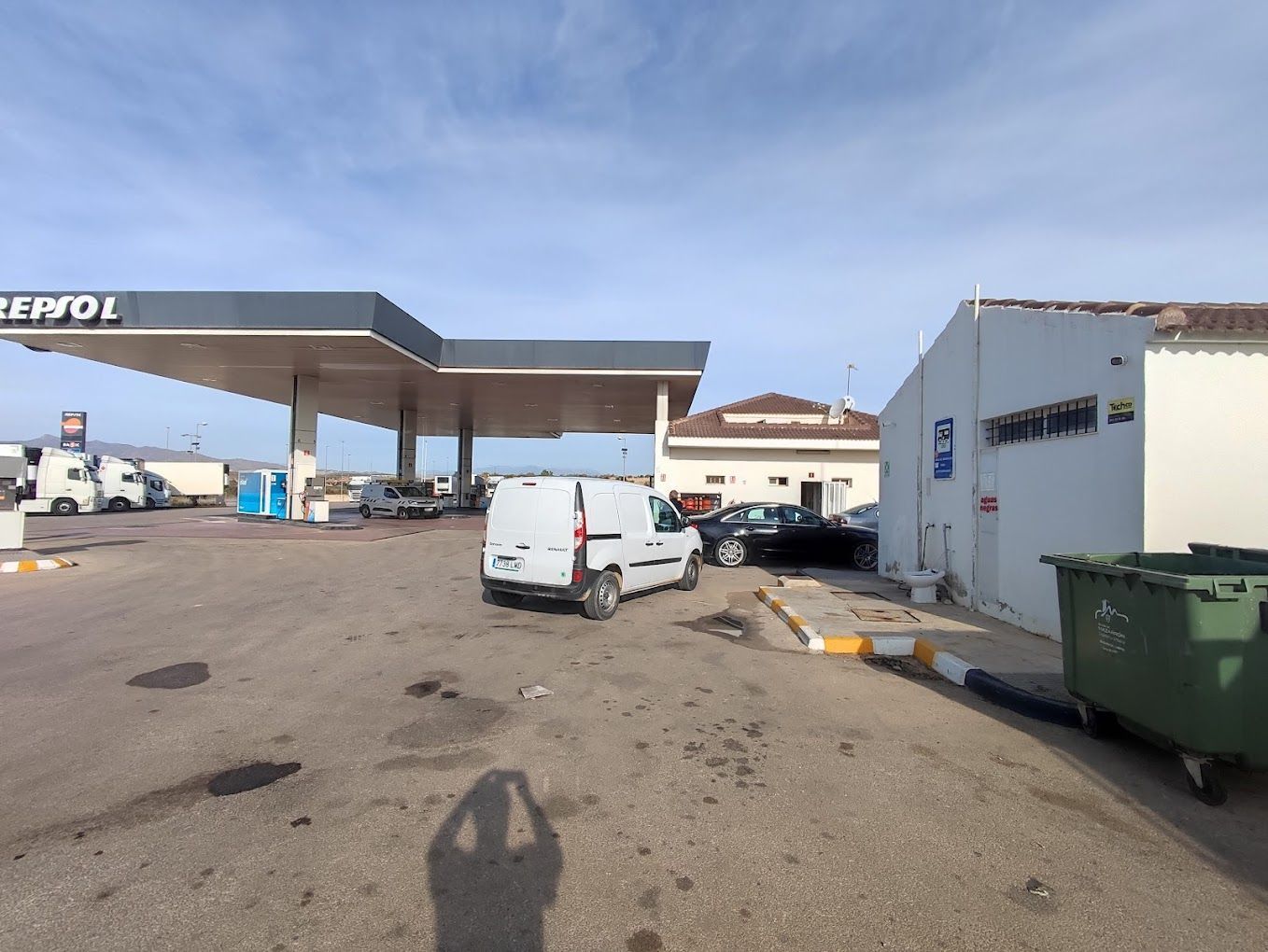 Una furgoneta blanca está aparcada delante de una gasolinera.