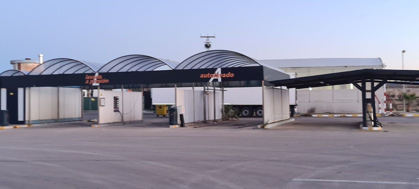 Un estacionamiento vacío con un lavado de autos al fondo.