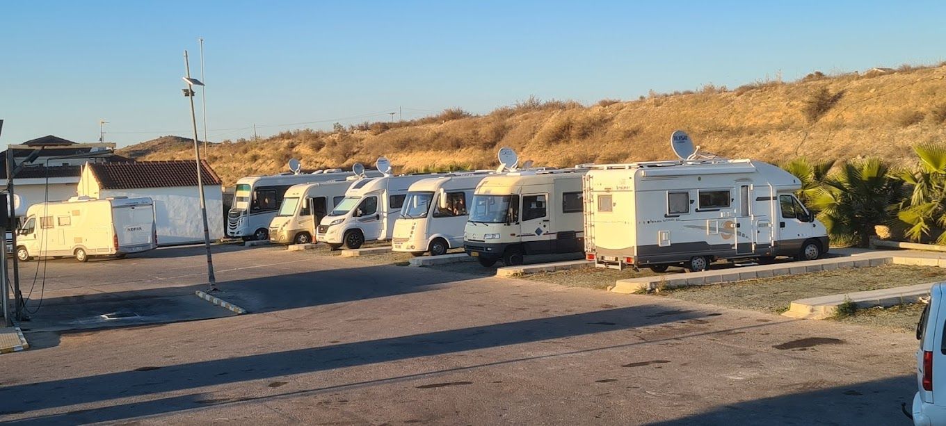 Una fila de vehículos recreativos están estacionados en un estacionamiento.