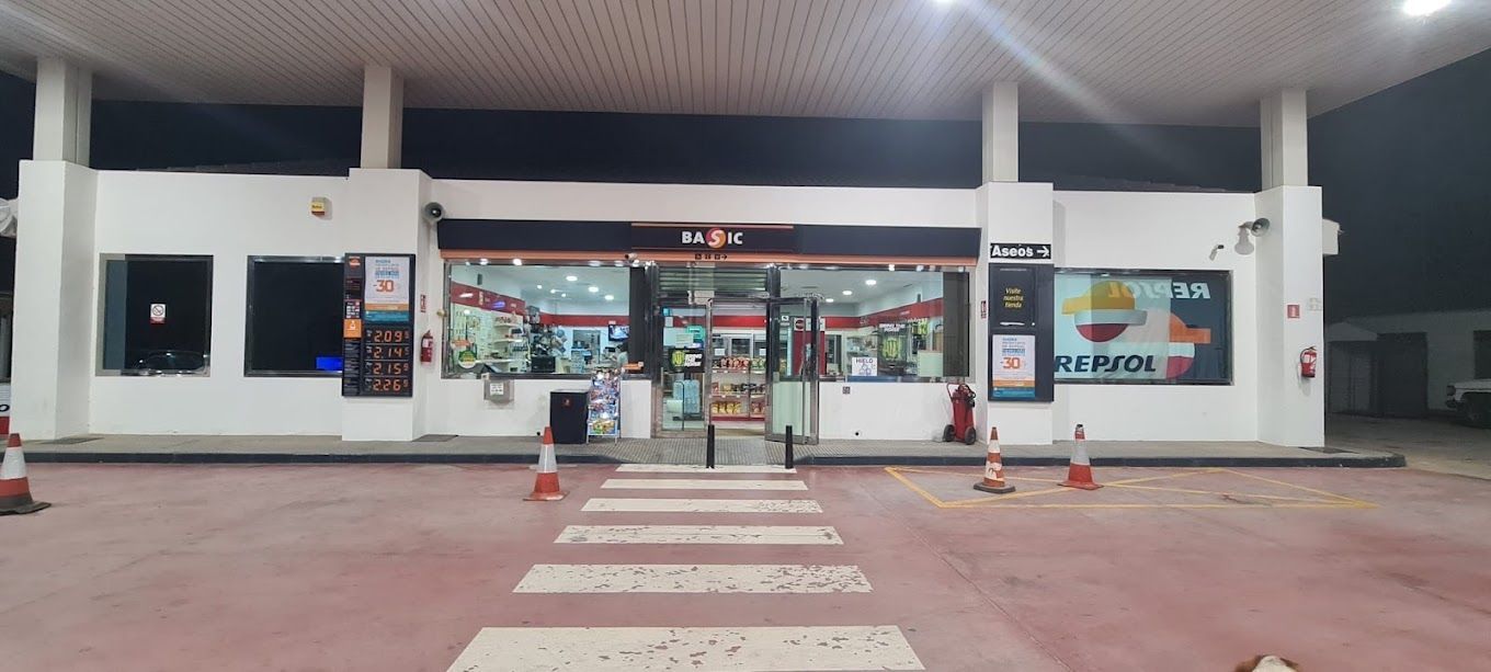 Una gasolinera de noche con un paso de peatones delante.