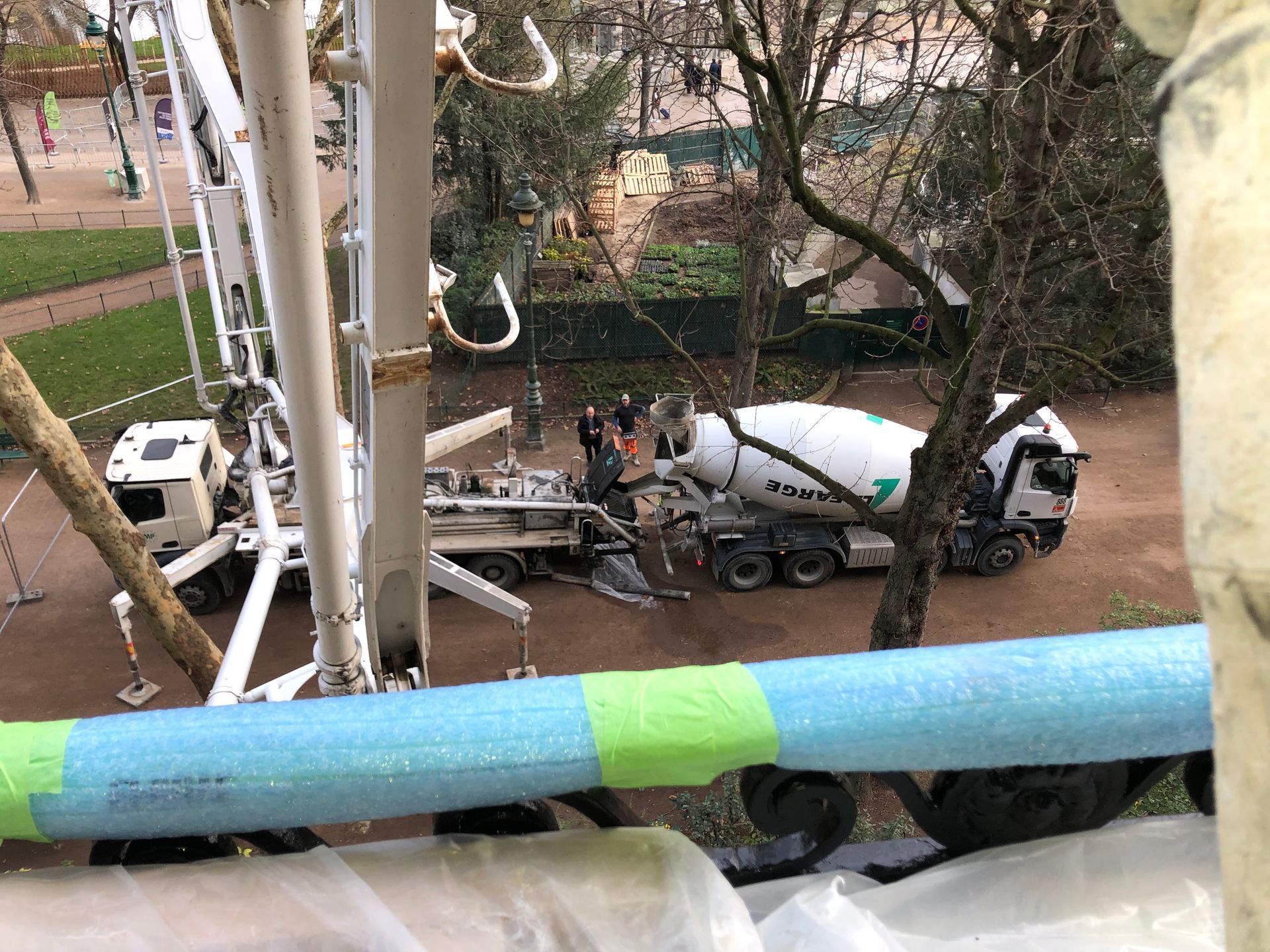 Un camion-citerne verse du béton sur un chantier de construction avec des ouvriers debout près des véhicules.