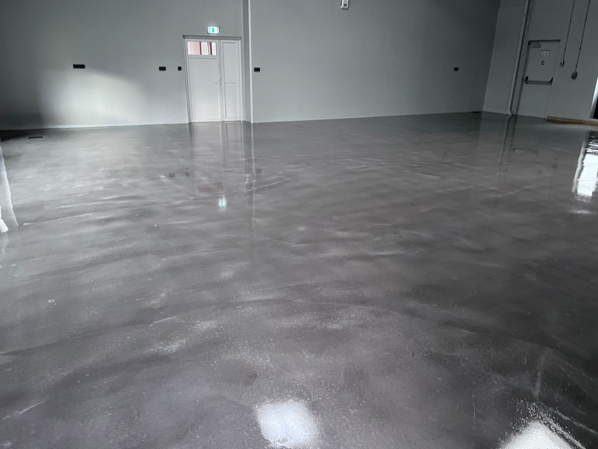 Hall intérieur gris vide avec un sol en béton brillant et des portes doubles sur le mur du fond