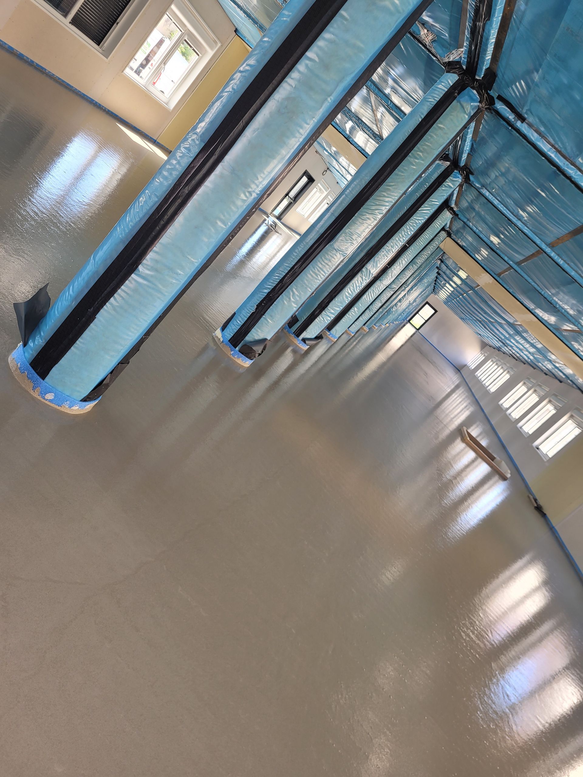 Trois supports de plantes tissés avec de la verdure contre un mur de béton gris, éclairé par la lumière du soleil.