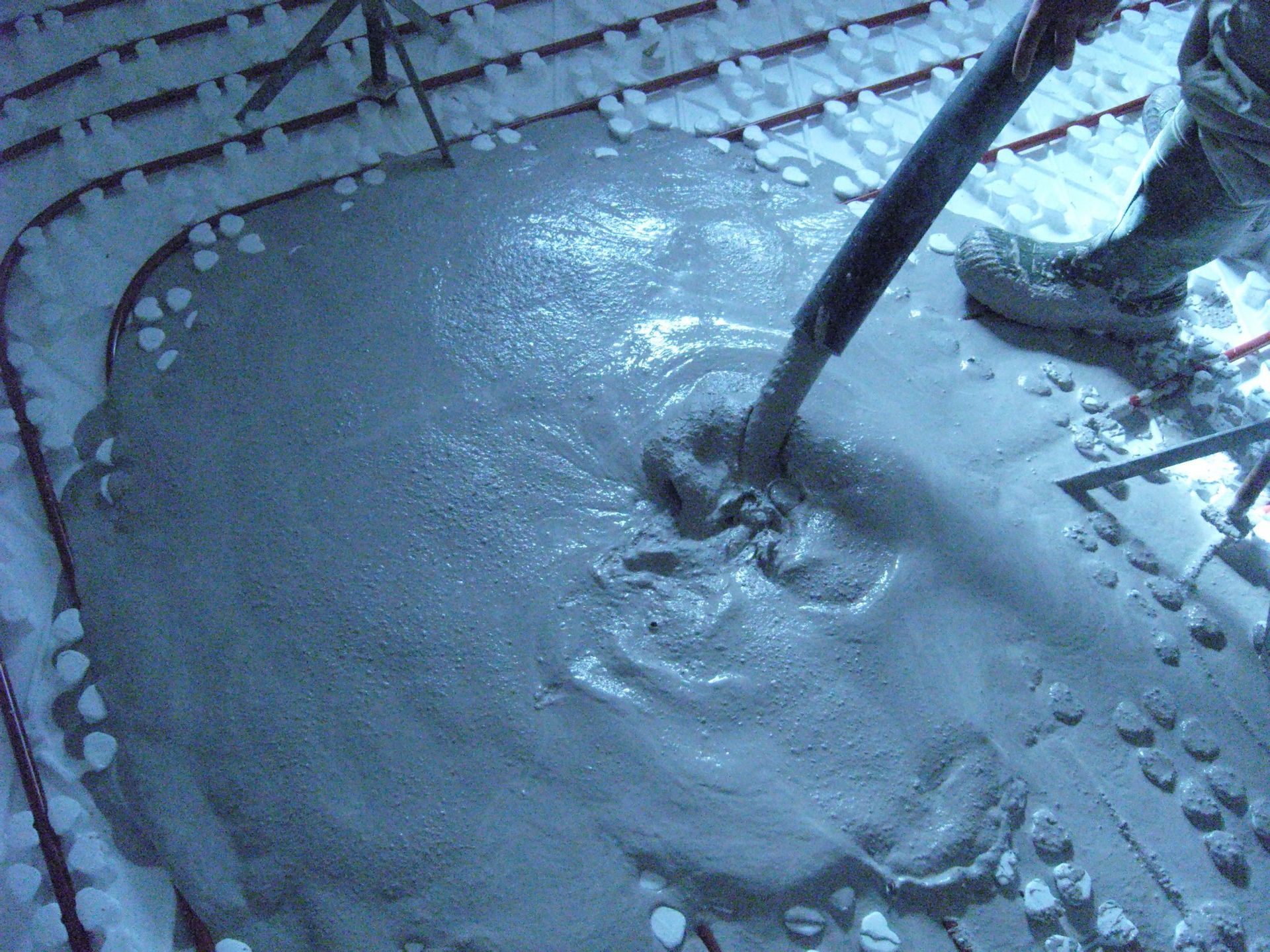 Coulage de béton humide sur des tuyaux de chauffage par le sol.