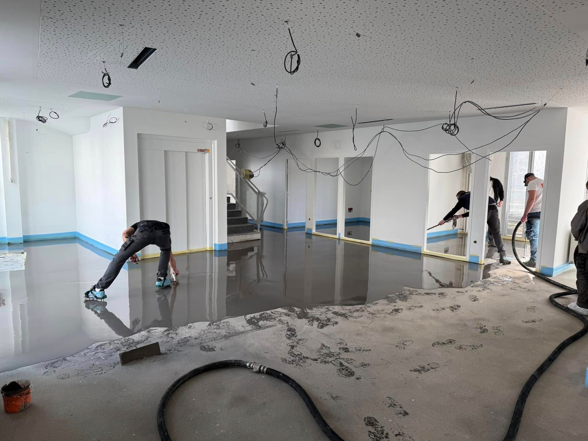 Ouvriers lissant une chape liquide.