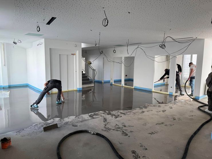 Ouvriers lissant une chape liquide.