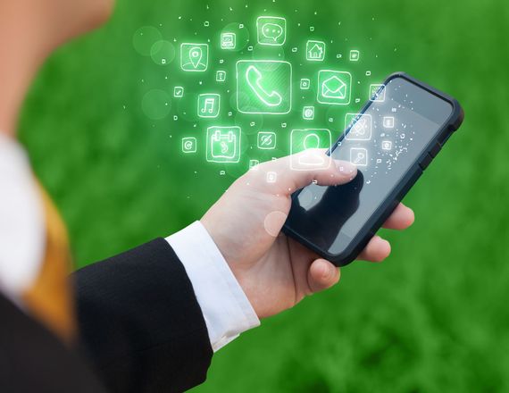 Personne en costume tenant un smartphone ; icônes d'application lumineuses.