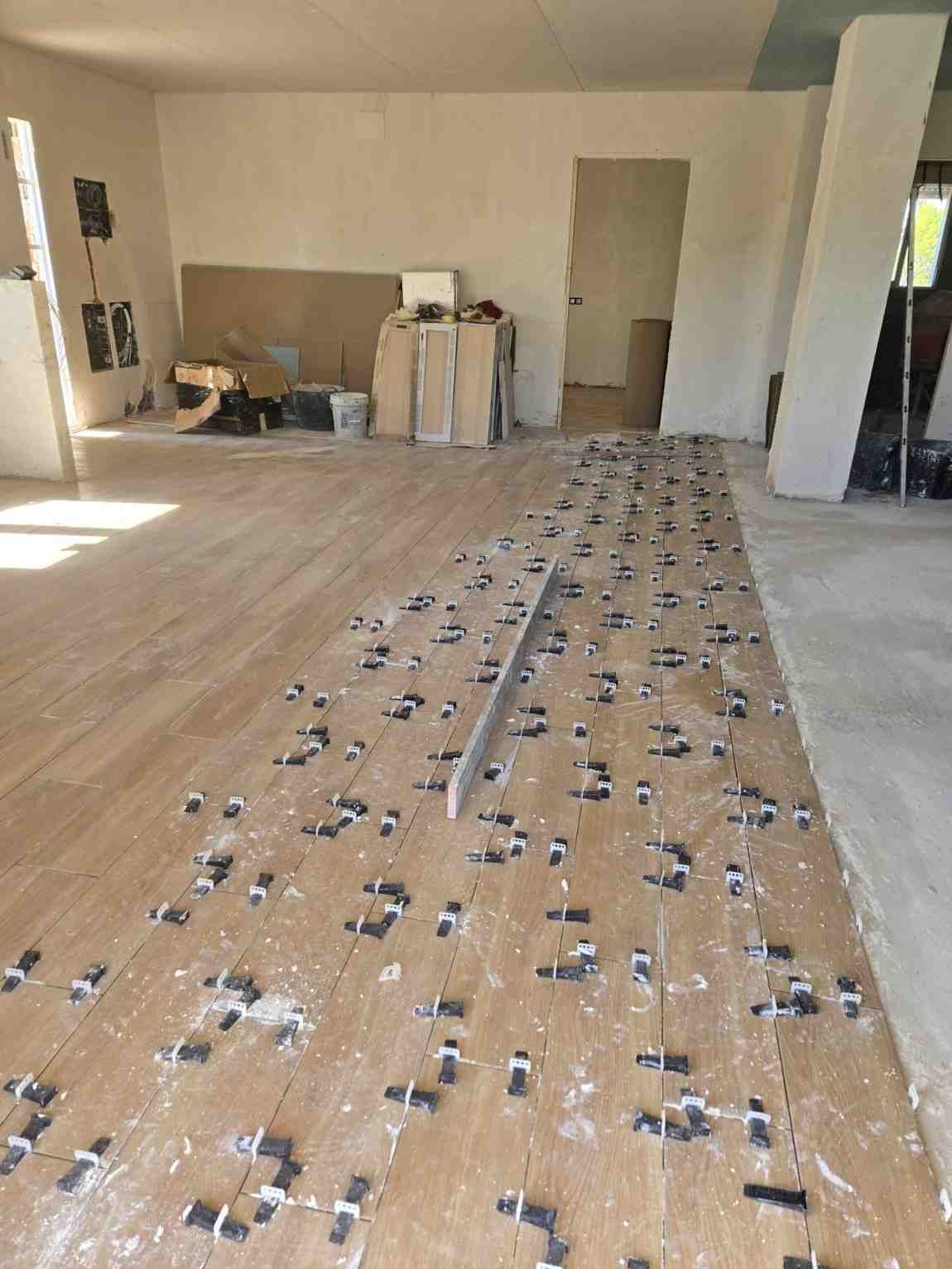 Habitación vacía con una larga franja de suelo cubierta de pequeños marcadores o separadores negros dispersos.