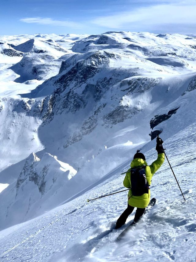 Skier on a steep snowy slope above a wide winter mountain landscape