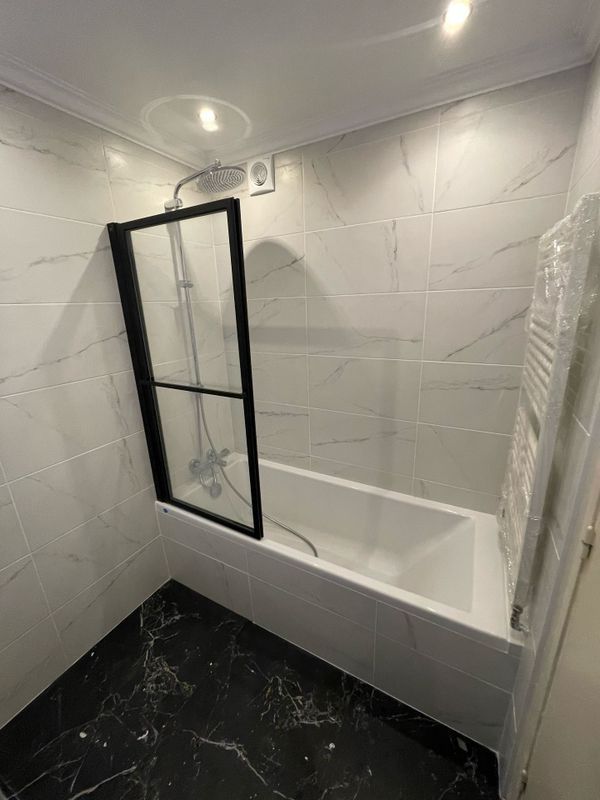 Une baignoire équipée d'une paroi en verre et un sèche-serviettes.