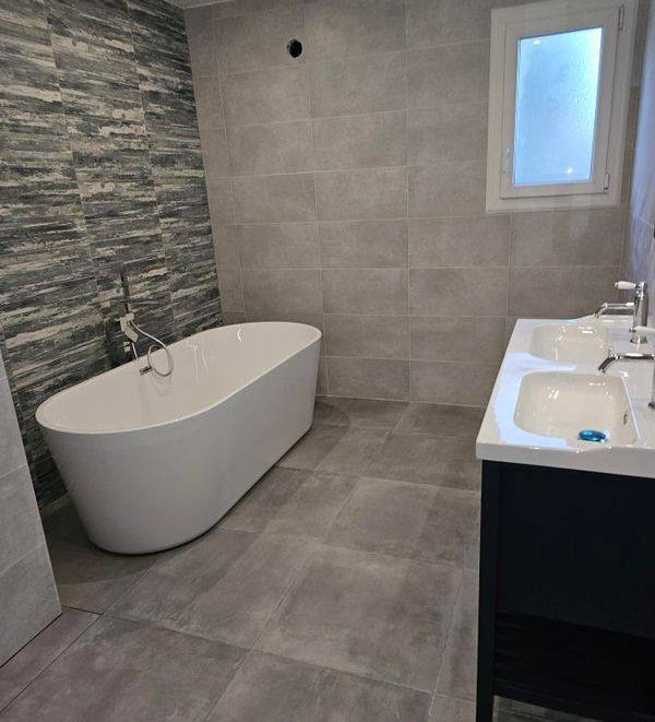 Une salle de bains moderne avec une baignoire îlot et un meuble à double vasque.
