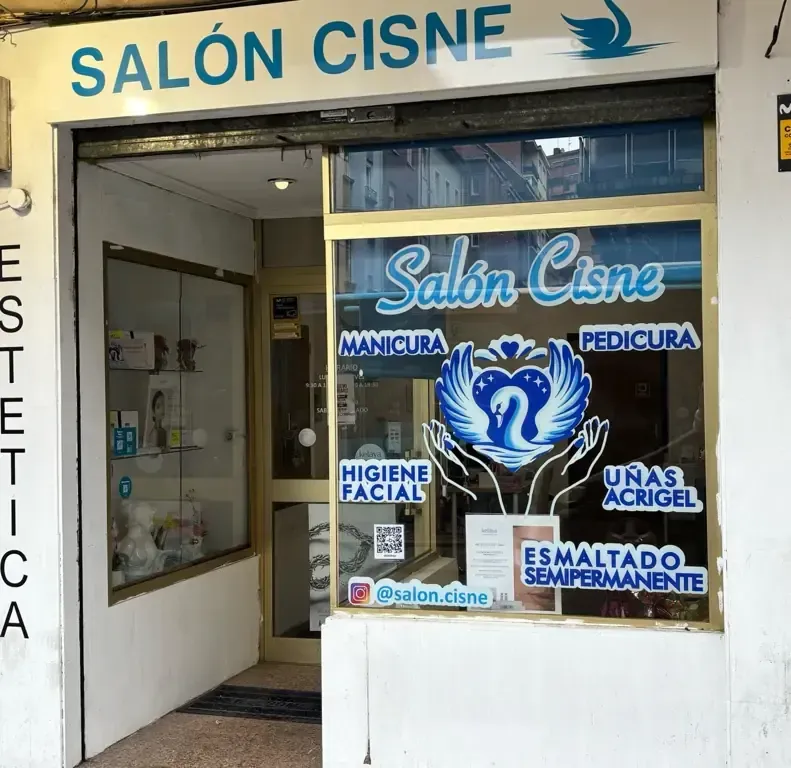 Interior de un salón de uñas con un logotipo de cisne en la pared y una estación de manicura.