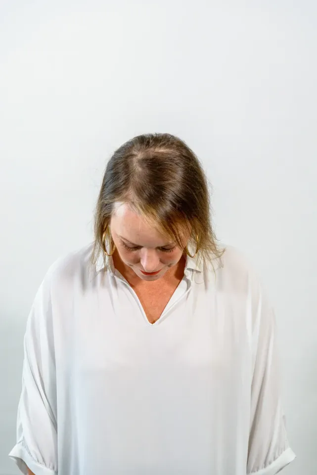 Una mujer con una camisa blanca mira su cabello.