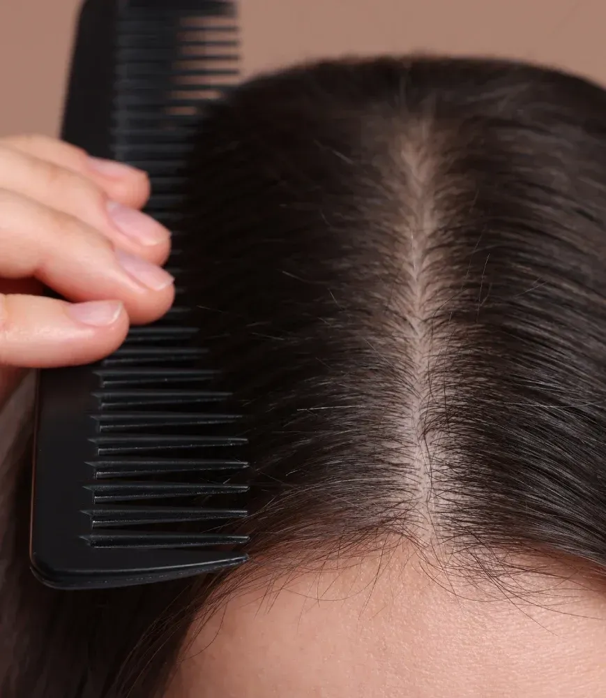 Una mujer se peina el cabello con un peine negro.