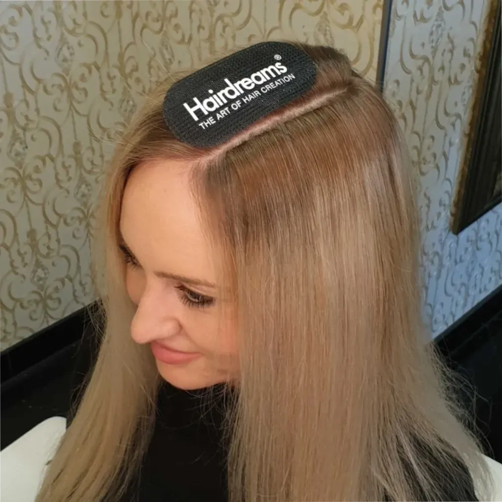 Una mujer con cabello largo y oscuro tiene las manos en la cabeza.