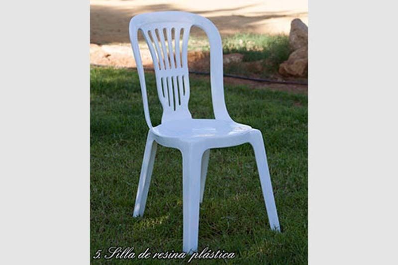 Una silla de plástico blanca está sentada en el césped.