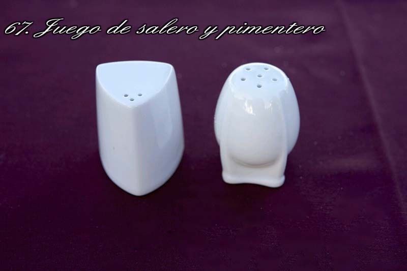 Dos saleros y pimenteros blancos sobre una superficie morada