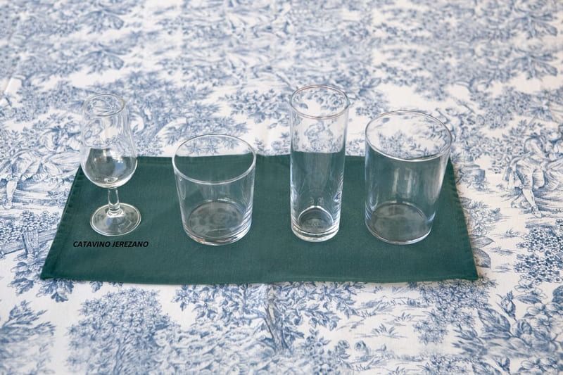 Cuatro vasos están alineados sobre una servilleta verde sobre una mesa.
