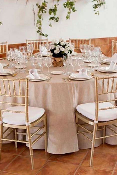 Una mesa con platos, vasos y un jarrón de flores encima.