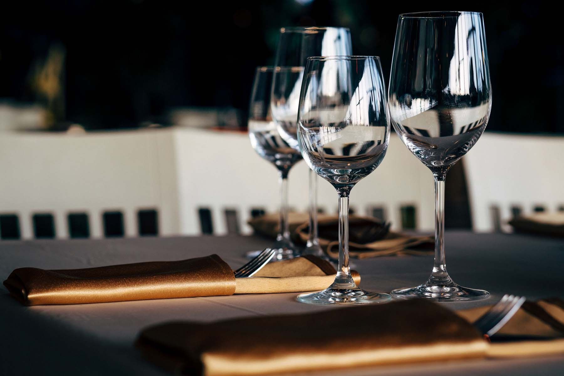 Hay tres copas de vino sobre una mesa con una servilleta y un tenedor.