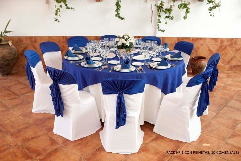 Una mesa con un mantel azul y sillas blancas.
