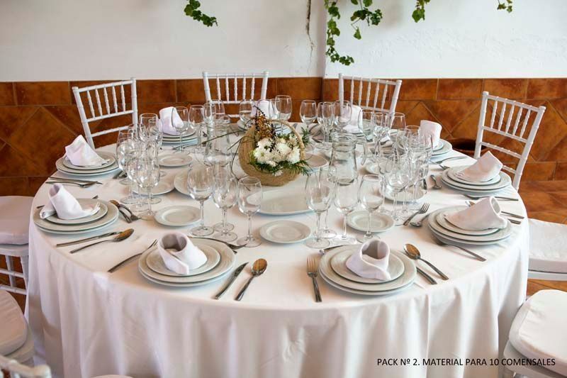 Una mesa con platos, cubiertos y un jarrón con flores encima.