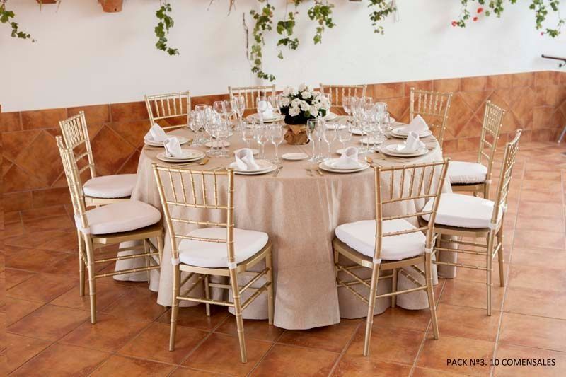 Una mesa preparada para una recepción de boda con mantel y sillas.
