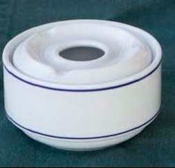 Un cenicero blanco con una raya azul está sobre una mesa.