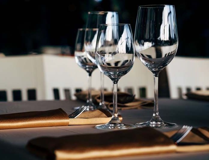 Tres copas de vino están sobre una mesa con servilletas doradas.