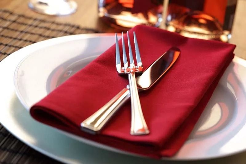 Un plato con una servilleta roja y cubiertos encima.