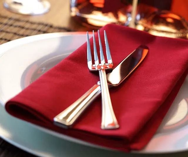 Cubiertos sobre una servilleta roja en un plato blanco