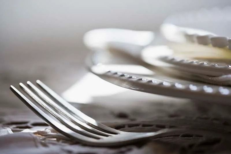 Un tenedor está junto a una pila de platos sobre una mesa.