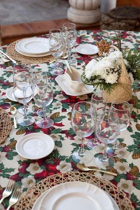 Una mesa con platos, copas de vino y flores.