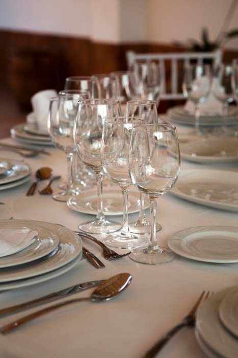 Una mesa puesta con platos, cubiertos y copas de vino.