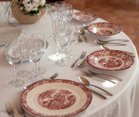 Una mesa está puesta con platos, vasos, tenedores, cucharas y cubiertos.