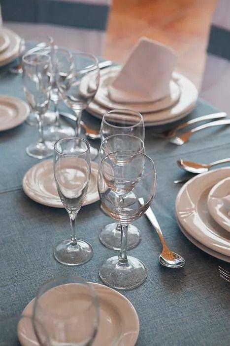 Una mesa puesta con platos, copas de vino, cubiertos y una servilleta.