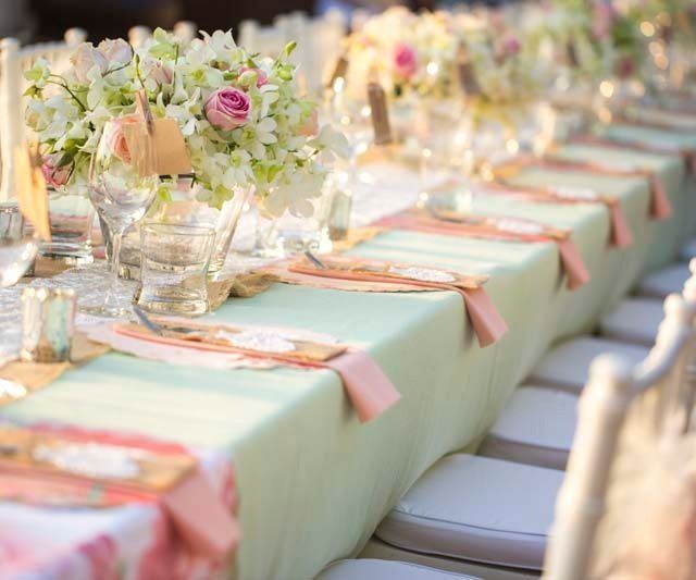 Una mesa larga preparada para una recepción de boda con flores.