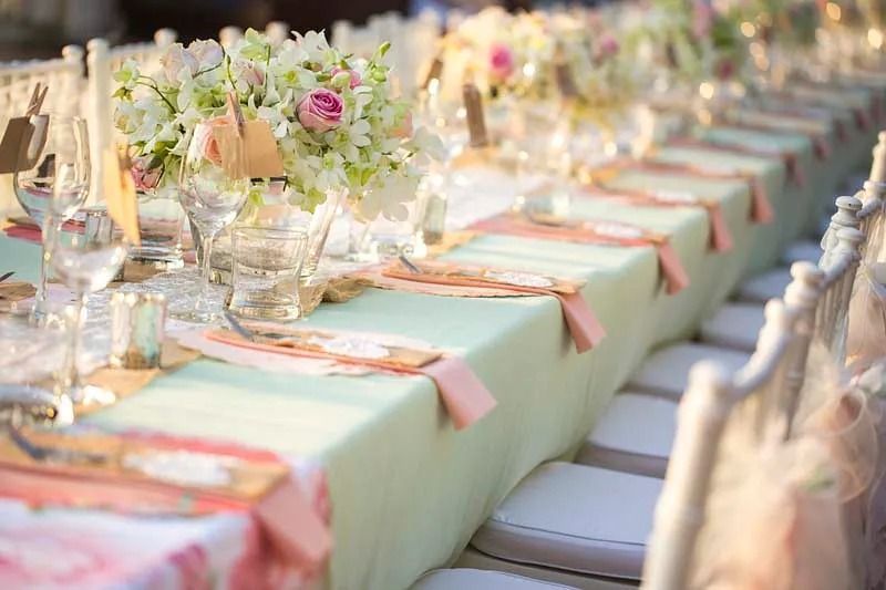 Una mesa larga preparada para una recepción de boda con flores.