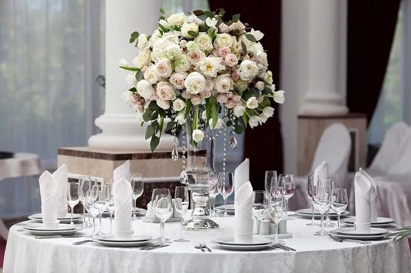 Una mesa preparada para una recepción de boda con un jarrón de flores encima.