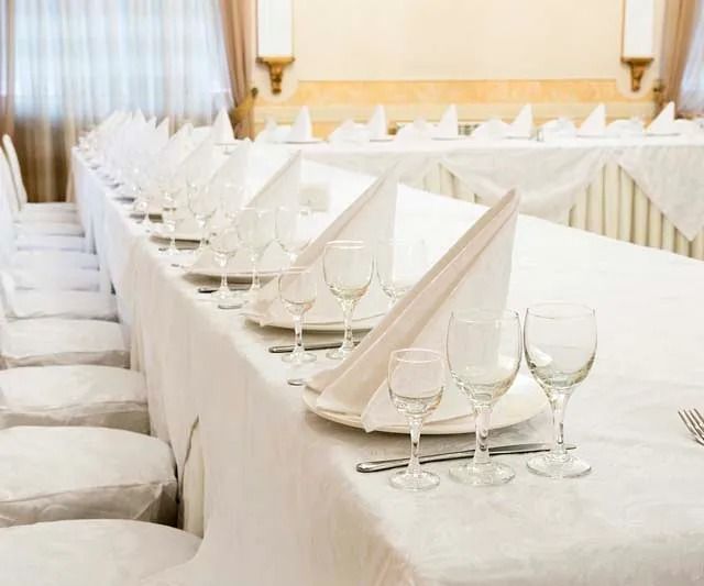 Una mesa larga con platos, vasos, cubiertos y servilletas sobre ella.