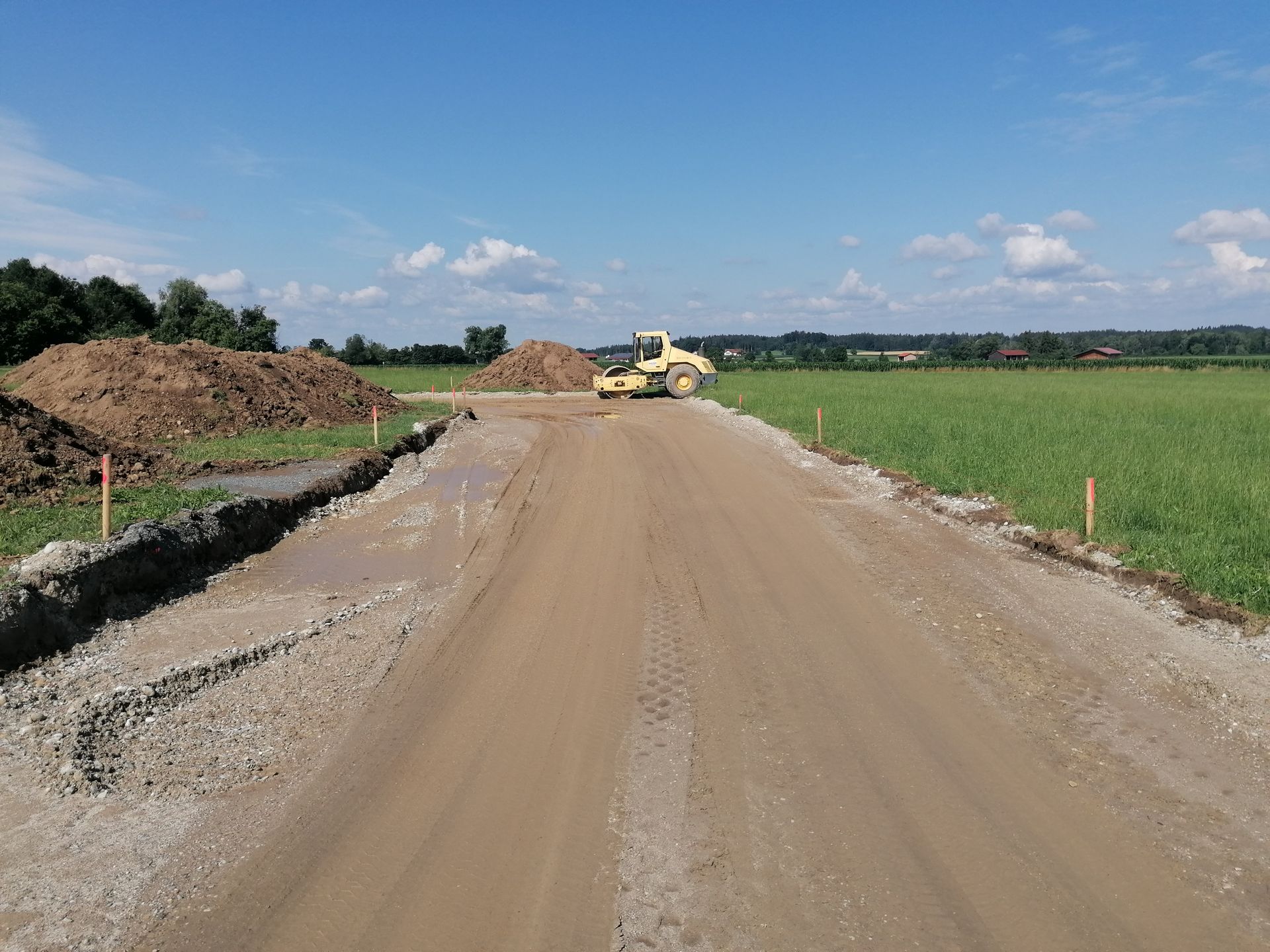 Planierte Schotterstraße mit Walze in ländlicher Umgebung